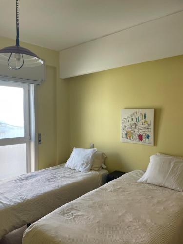 two beds in a room with a window at VRS - PORTO BEACH FLAT in Porto