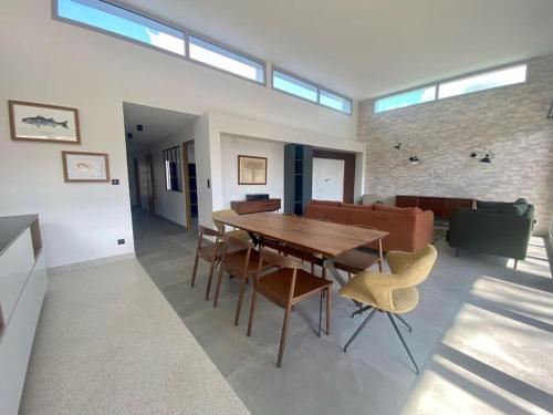 un salon avec une table et des chaises en bois dans l'établissement Villa Romane Piscine Proche Circuit 24h, à Brette-les-Pins