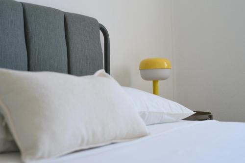 a bed with white pillows and a yellow lamp at AR apartments in Lamezia Terme