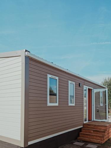 a small house with a wooden siding and windows at Super Cordelia - Camping Belle-Vue in Berdorf