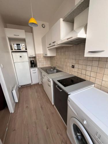 - une petite cuisine avec des placards blancs et un lave-vaisselle dans l'établissement Comtesse, à La Rochelle