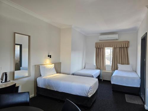 a hotel room with two beds and a mirror at Country Lodge Motor Inn in Bathurst