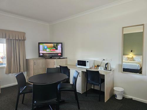 a hotel room with a table and chairs and a television at Country Lodge Motor Inn in Bathurst