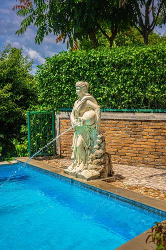 a statue sitting next to a swimming pool at Hotel Deli River and Restaurant Omlandia in Medan