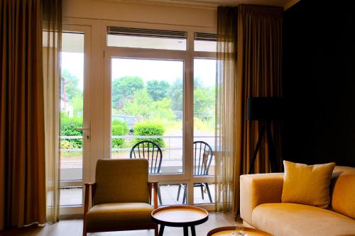 a living room with a couch and chairs in front of a window at La Dominotte short stay apartment 9a in Arcen