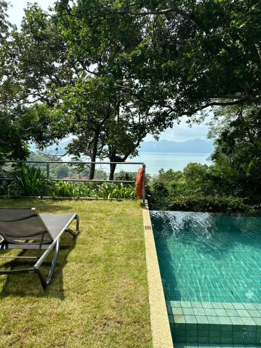 a pool with a table and a bench in the grass at Ambong Pool Villas - Private Pool in Pantai Cenang