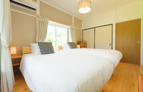 a bedroom with two white beds and a window at Togari Inn Suites in Iiyama