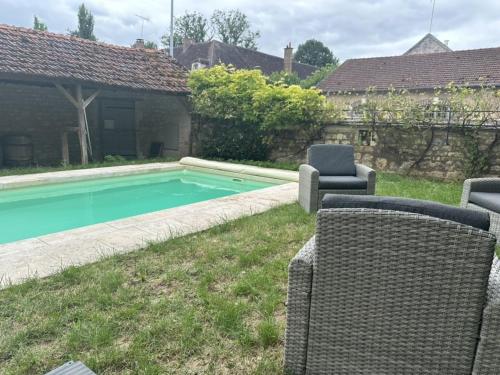 a swimming pool in a yard with chairs and a house at La Maison du Chablisien in Chablis