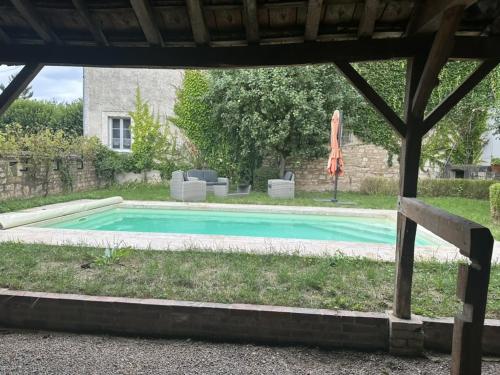 a swimming pool in a yard with an umbrella at La Maison du Chablisien in Chablis