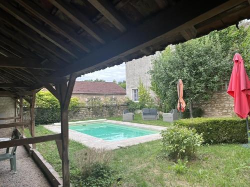 a backyard with a swimming pool and an umbrella at La Maison du Chablisien in Chablis