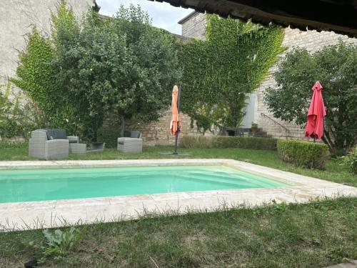a swimming pool with an orange umbrella and an umbrella at La Maison du Chablisien in Chablis