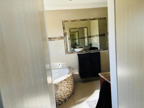a bathroom with a tub and a sink and a mirror at Round Robben in Langebaan