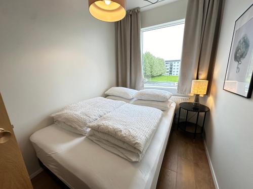 - une chambre avec 2 lits avec des couvertures blanches et une fenêtre dans l'établissement Apartment in Fellsmúli Reykjavik - Birta Rentals, à Reykjavik