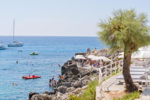a group of people swimming in the water at a beach at Hotel La Roccia in Castro di Lecce