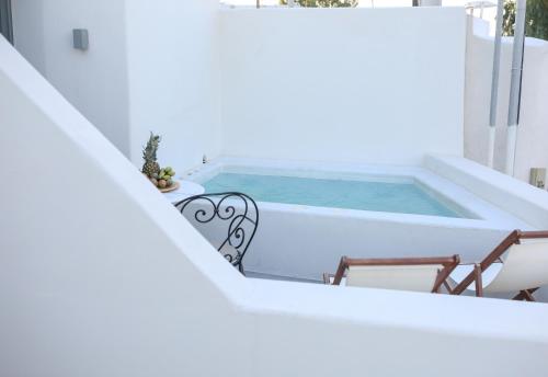 a plunge pool on a balcony with chairs and a bench at La Maltese Estate in Imerovigli