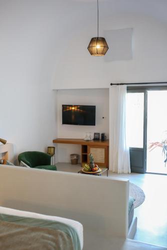 a white living room with a couch and a tv at La Maltese Estate in Imerovigli