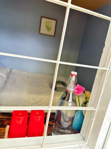 a shelf with a bottle and four red cups at Thương House in Da Lat