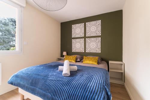 - une chambre avec un lit bleu avec des oreillers jaunes et une fenêtre dans l'établissement Le Cocon d'Adamille - Appt avec piscine partagée, à Tournefeuille