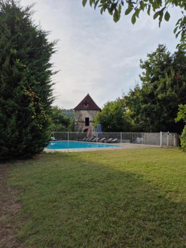 a swimming pool with a building behind a fence at Chateau de Presque in Saint-Médard-de-Presque