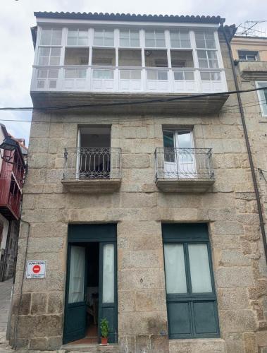 a stone building with two windows and a balcony at A Casa do Sastre1 in Ribadavia