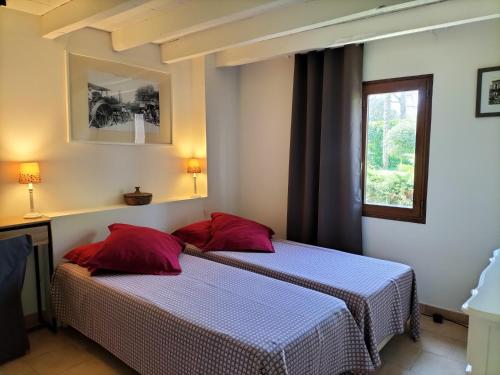 two beds in a room with two red pillows at Gite L'Etable d'en Naoua in Maubec