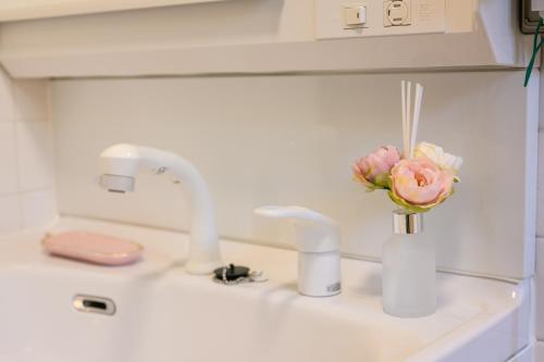 a bathroom sink with two faucets and a vase of flowers at 最大10名 北谷アメリカンビレッジ8分 宮城海岸4分の長期滞在におすすめ コーラルハウス北谷 in Chatan