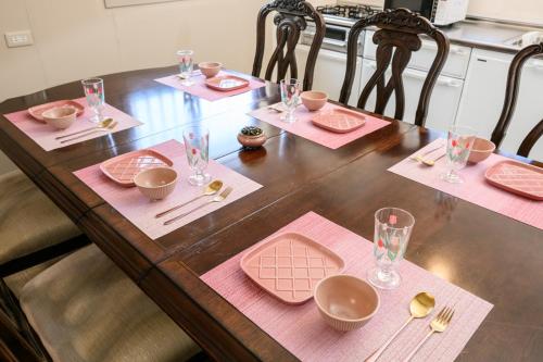 a wooden table with pink napkins and glasses on it at 最大10名 北谷アメリカンビレッジ8分 宮城海岸4分の長期滞在におすすめ コーラルハウス北谷 in Chatan