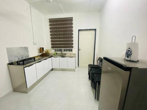 a kitchen with white cabinets and black counter tops at Golf Avenue Homestay Kota Bharu in Pengkalan Cepa