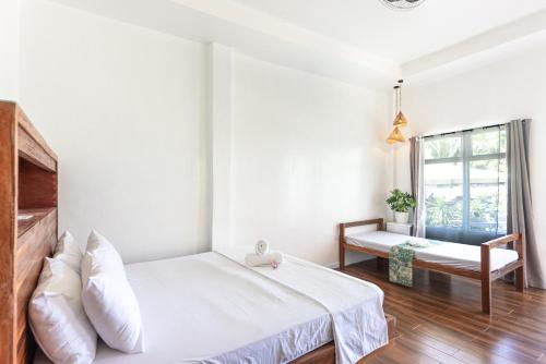 a white bedroom with a bed and a window at YAMA APARTMENTS - Private Beachfront in General Luna