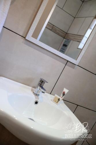 a bathroom sink with a faucet and a mirror at Bellerose Guesthouse in Klerksdorp