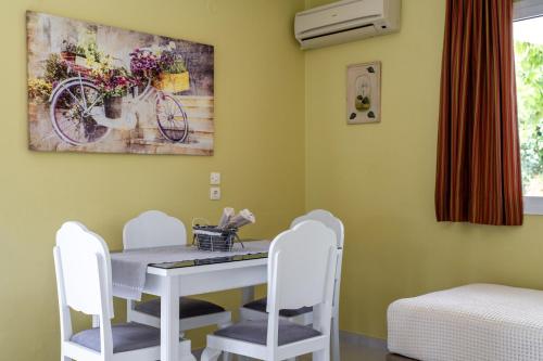 a dining room with a white table and white chairs at Studios Rania - Rania Studios & Apartments in Lassi