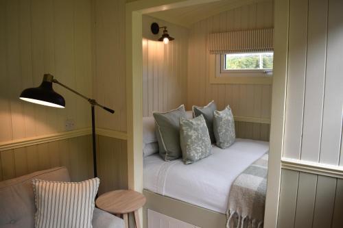a small room with a bed with pillows and a lamp at Ardmore Shepherd's Hut in Lochinver