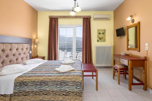 a hotel room with a bed and a desk and a window at Studios Rania - Rania Studios & Apartments in Lassi