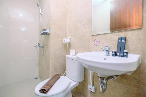 a bathroom with a toilet and a sink and a shower at Well Designed 2BR Corner Transpark Cibubur Apartment By Travelio in Depok