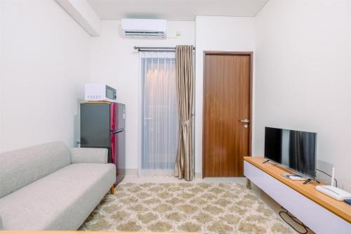 a living room with a couch and a television at Well Designed 2BR Corner Transpark Cibubur Apartment By Travelio in Depok