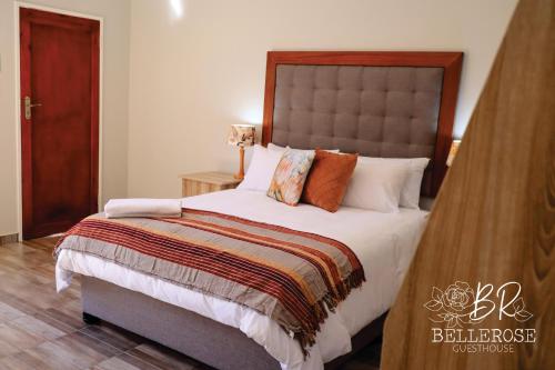 a bedroom with a large bed with pillows at Bellerose Guesthouse in Klerksdorp