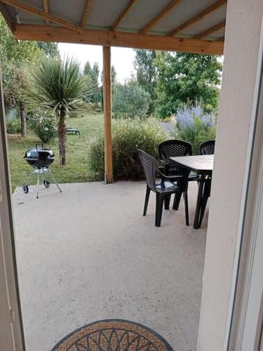 a patio with a table and chairs and a grill at Maison à la campagne in Meursac
