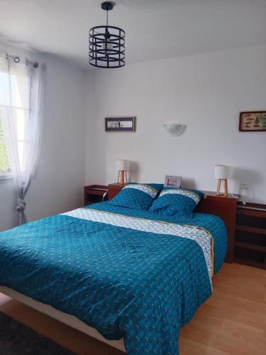 a bedroom with a bed with a blue comforter at Maison à la campagne in Meursac