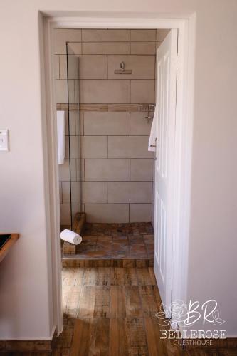 a bathroom with a shower with a wooden floor at Bellerose Guesthouse in Klerksdorp