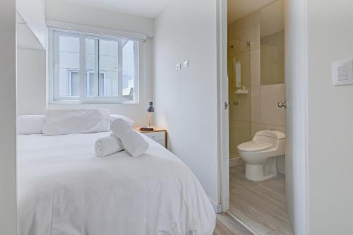 a white bedroom with a bed and a toilet at Quark Apartments in Lima