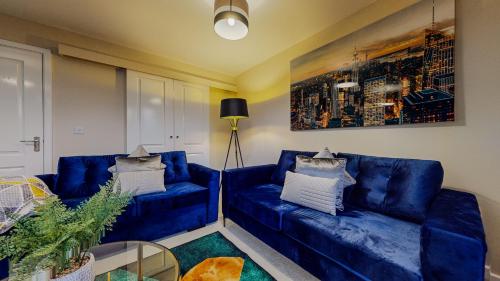 a living room with two blue couches and a painting at Spacious 4 Bedroom, 3 Bath House by Jesswood Properties Contractors, Business and Leisure with Free Parking and WIFI in Peterborough