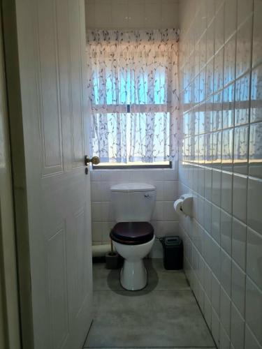 a bathroom with a toilet with a wooden seat and a window at Point Village Accommodation - Galathea 6 in Mossel Bay