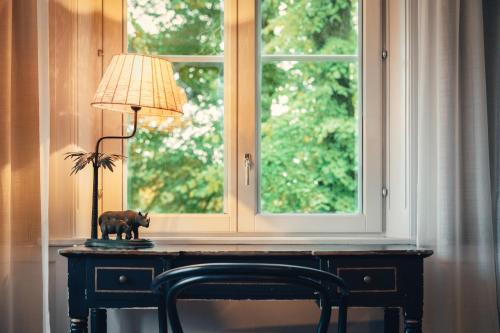 a lamp on a table in front of a window at Stallmästaregården Hotel, Stockholm, a Member of Design Hotels in Stockholm