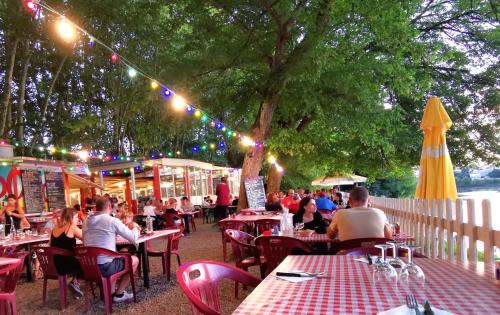 un groupe de personnes assises à des tables dans un restaurant en plein air dans l'établissement Proche Saint-Émilion, confortable gîte rénové avec terrasse - 2 personnes, à Sainte-Terre