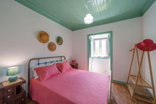a bedroom with a bed with pink sheets and a window at Casa Alba, desde 1926 in Alvados