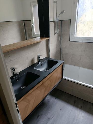 La salle de bains est pourvue d'un lavabo noir et d'une douche. dans l'établissement Appartement cosy au pied du MtBlanc, à Chamonix-Mont-Blanc
