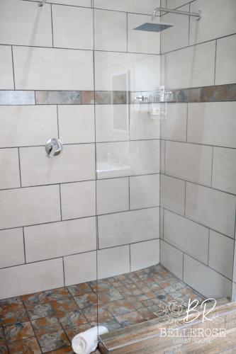 a shower with a glass door and a sink at Bellerose Guesthouse in Klerksdorp