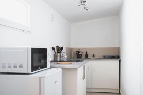 une cuisine avec des armoires blanches et un micro-ondes dans l'établissement Studio Le Fresne, à Sainte-Gemme-sur-Loire