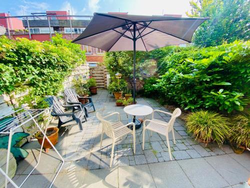 a patio with a table and chairs and an umbrella at Private studio, patio garden and free car parking in Amsterdam