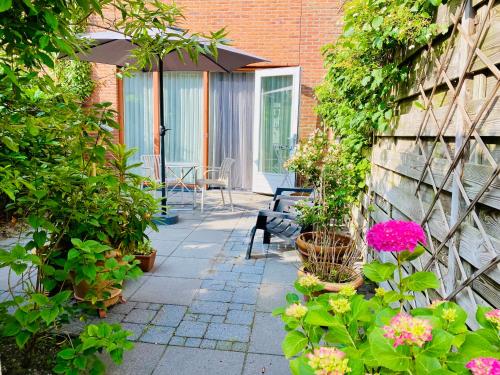 a patio with plants and flowers and an umbrella at Private studio, patio garden and free car parking in Amsterdam